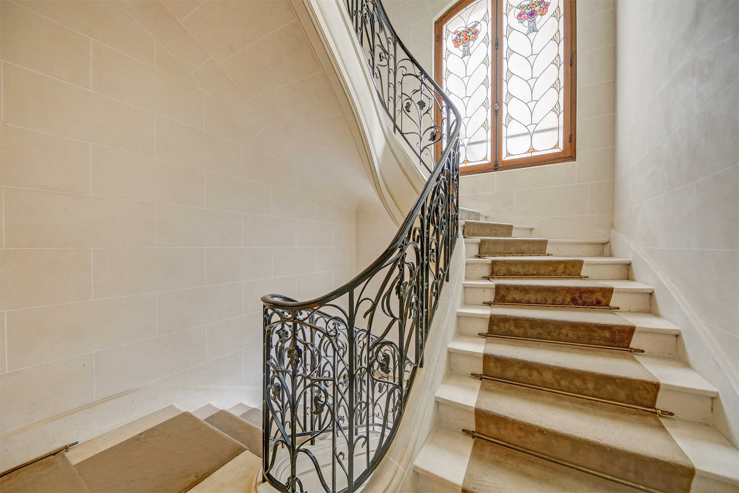 Elegant Art Nouveau staircase with wrought iron railings and fresh orchids at Maison Scheffer